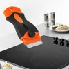 A scraper is shown being used on a glass-ceramic stovetop, with a plate of food in the background. Náhled obrázku produktu