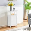 A white bathroom cabinet with a vase of sunflowers and a clock on top, placed in a room with a plant and a sofa. Produktbild-Vorschau