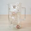 A glass pitcher filled with crumpled plastic bottles. Náhled obrázku produktu