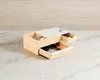 A wooden jewelry box with multiple drawers and compartments, displaying sunglasses, an orange object, and small items within its open drawers. Voir les images du produit