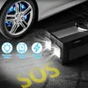 A car tire and a black portable device are shown on a dark, asphalt-like surface with yellow "SOS" text, and icons indicating features. Produktbild-Vorschau