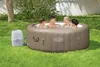 Four people relaxing in an inflatable hot tub in a grassy backyard. Produktbild-Vorschau