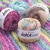 Four balls of yarn in various ombre colorways are arranged on a colorful knitted background. Produktbild-Vorschau