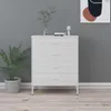 A white dresser with four drawers stands against a gray wall, next to a potted plant. Náhľad obrázku produktu