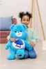 A young girl is holding a large blue plush bear. Produktbild-Vorschau