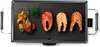 A close-up, top-down view of a black electric grill with food on it. Podgląd zdjęcia produktu