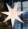 A white paper star lantern hangs in front of a blurred background of lights and a window. Voir les images du produit