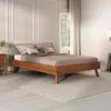 A modern wooden bed frame with pillows and bedding in a bedroom setting. Produktbild-Vorschau