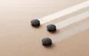 Three black robot vacuums are shown on a light wood floor, each leaving a faint, translucent trail behind it, suggesting movement and cleaning. Produktbild-Vorschau