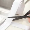 A roll of white sealing tape is being cut with scissors next to a sink. Náhľad obrázku produktu