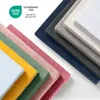 A collection of folded fabric swatches in various colors, arranged diagonally, with a certification logo and text in the upper left corner. Voir les images du produit