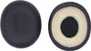 Two black ear pads for headphones are shown against a white background. One ear pad is shown from the outside, with a perforated surface. The other ear pad is shown from the inside, revealing the foam padding. Voir les images du produit