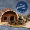 A wooden pet house, a bowl of dried crickets, and a piece of bark are arranged on a textured surface, with a dark gray background. Produktbild-Vorschau