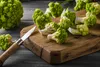 A close-up shot of Romanesco broccoli florets on a wooden cutting board, with a knife nearby. Voir les images du produit