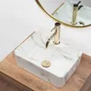 A close-up, overhead view of a rectangular marble-patterned sink with a gold faucet, placed on a wooden countertop. Podgląd zdjęcia produktu