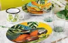 A collection of tropical-themed tableware, including plates, a mug, and glasses, arranged on a marble surface. Anteprima dell’immagine prodotto