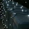 A string of white LED lights draped over a stone wall at night. Produktbild-Vorschau