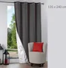 A dark gray curtain is partially drawn, revealing a white lining and a view of greenery outside. A beige armchair with a red cushion sits in the foreground. Podgląd zdjęcia produktu