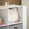 A white storage unit with shelves and drawers, containing a stuffed toy and books. Podgląd zdjęcia produktu