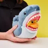 A person is holding a plush toy of a shark with a duck inside its mouth. Podgląd zdjęcia produktu