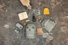 A collection of items laid out on a textured surface, including a backpack, skateboard, headphones, and other accessories. Produktbild-Vorschau