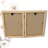 A close-up, top-down view of a wooden, hinged double picture frame, shown from the back with the cardboard inserts visible. Decorative floral elements are subtly visible in the background. Produktbild-Vorschau
