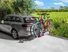 A gray station wagon with two bicycles mounted on a rear rack, parked on a paved surface with a grassy field and trees in the background. Podgląd zdjęcia produktu