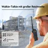 A construction worker holding a walkie-talkie with a building under construction in the background. Voir les images du produit
