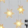 A string of snowflake-shaped LED lights hanging against a light gray background, with a power adapter visible on the right. Voir les images du produit