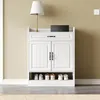 A white shoe cabinet with two doors and a drawer, placed against a light beige wall. Produktbild-Vorschau