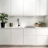 A clean, modern kitchen counter with white cabinets, a sink, faucet, and stovetop. Produktbild-Vorschau