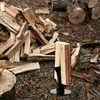 A manual log splitter is shown in a pile of firewood outdoors. Produktbild-Vorschau