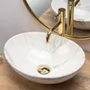 A close-up shot of a marble-patterned vessel sink with gold fixtures on a wooden countertop. Produktbild-Vorschau