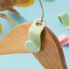 A light green hanger hook on a wooden hanger with a blue background. Produktbild-Vorschau