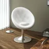 A white faux leather armchair with a chrome base is shown in a room with wooden flooring and a floor lamp. Náhled obrázku produktu