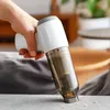 A hand holding a cordless handheld vacuum cleaner, cleaning a surface with some debris. Produktbild-Vorschau
