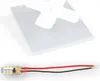 A white acrylic glass panel with a white cross-shaped object on top, and a small LED light strip with red and black wires below it, all on a white background. Produktbild-Vorschau