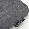 A close-up shot of a gray felt cushion with a black label showing care symbols. Produktbild-Vorschau