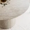 Close-up of a round dining table with a fluted base. Produktbild-Vorschau
