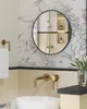 A modern bathroom with a round mirror and gold fixtures. Produktbild-Vorschau