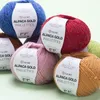 Several balls of yarn are arranged in a pile on a light green surface. Produktbild-Vorschau