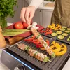A person is grilling skewers of meat and vegetables on an electric grill. Voir les images du produit