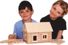 Two children are smiling behind a wooden log cabin building set. Anteprima dell’immagine prodotto