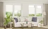 A living room scene with a sofa, coffee table, plants, and windows covered by pleated blinds. Produktbild-Vorschau