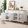 A white sideboard with a wooden top, featuring three drawers and four doors, is displayed in a well-lit room with a large window and plants. Anteprima dell’immagine prodotto