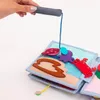 A hand holding a fishing rod with a string attached to a felt book with ocean-themed characters. Produktbild-Vorschau