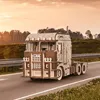 A wooden model truck driving on a road during sunset. Produktbild-Vorschau