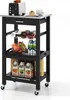 A black kitchen cart with a stainless steel top, filled with various items including a toaster, cake, drinks, and fruit. Náhled obrázku produktu