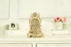 A decorative wooden clock sits on a white dresser with a framed photo and flowers in the background. Voir les images du produit