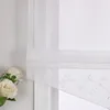 A close-up view of a white sheer Roman blind with embroidered floral and vine patterns, partially covering a window. White roses are visible in the foreground. Produktbild-Vorschau